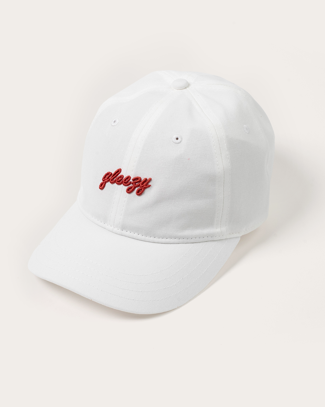 White dad hat with the Gleezy script logo embroidered in red