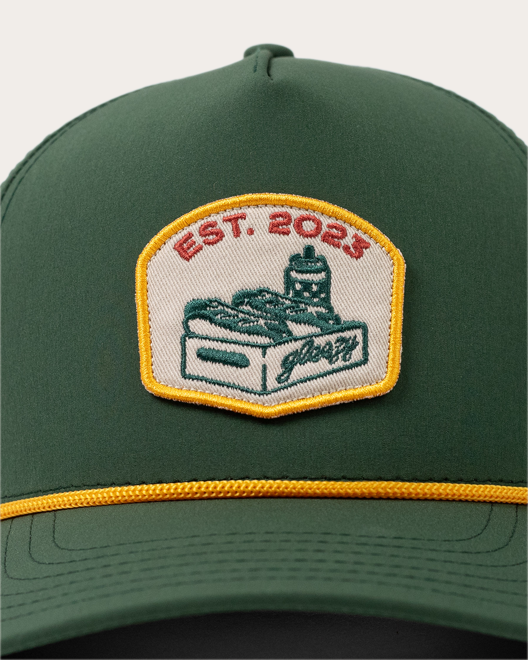 Close-up of the embroidered Gleezy hot dog box patch on the green performance hat