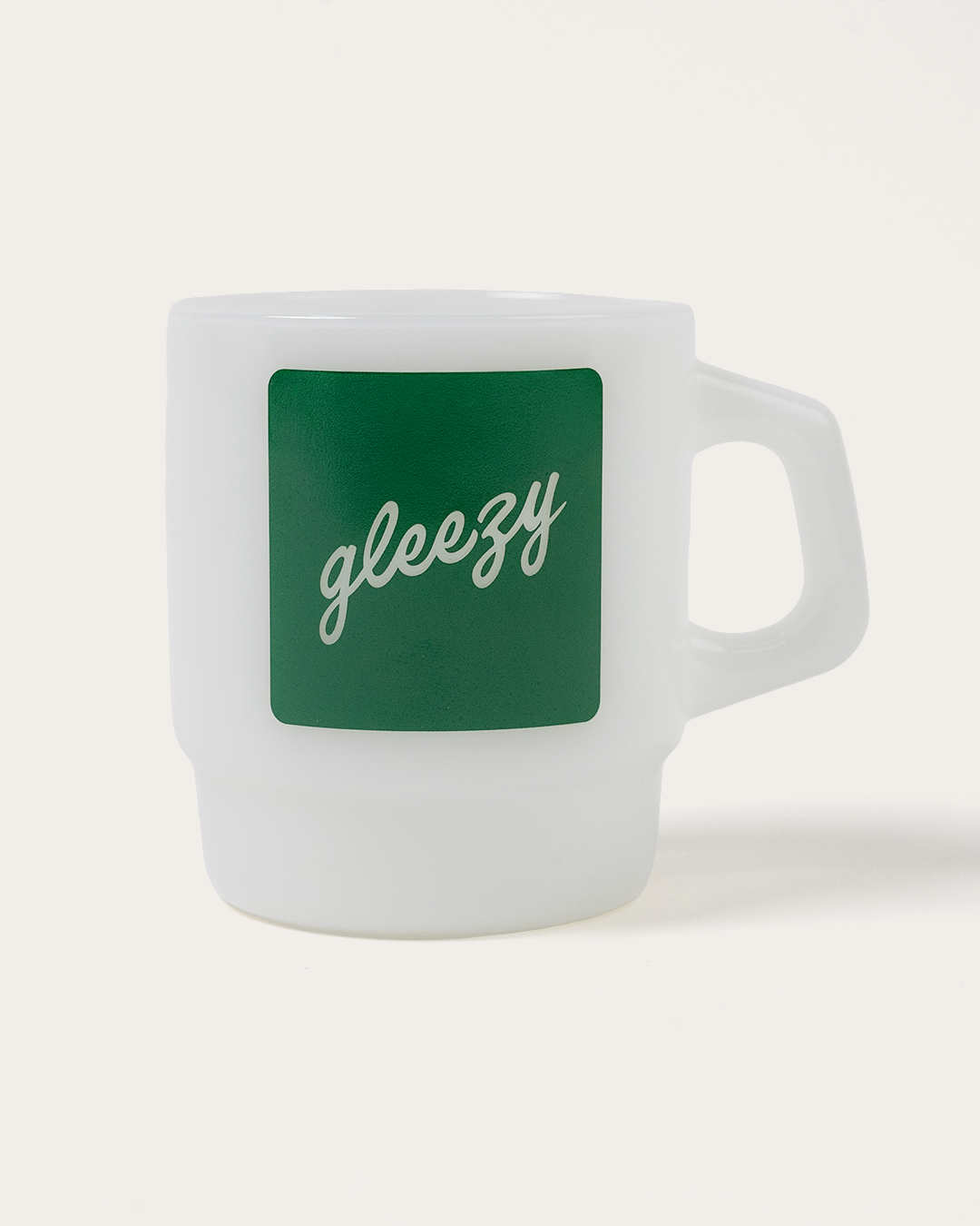 White mug with a green square featuring the word 'gleezy' on a white background