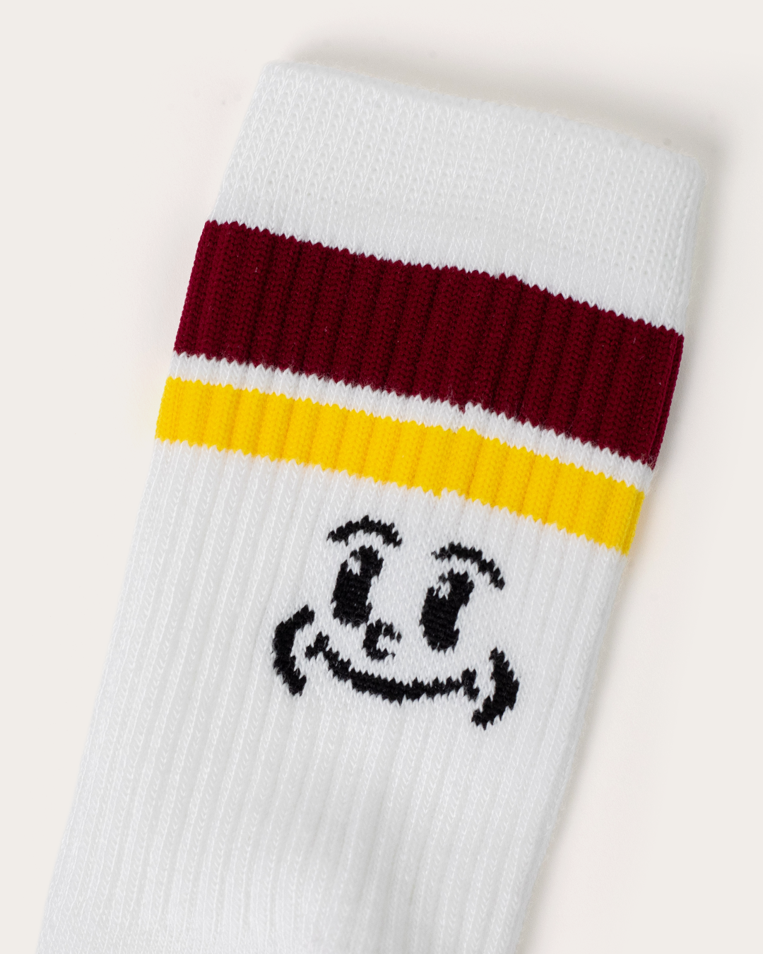 Close-up of a white crew sock with maroon and yellow stripes and a Gleezy smiley icon