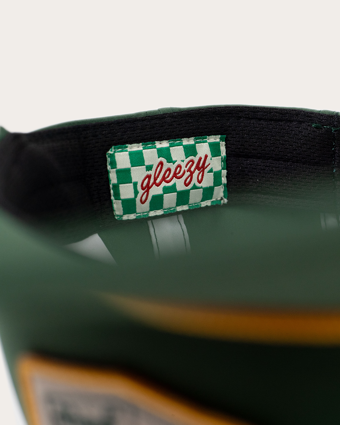 Close-up of the green-and-white checkered Gleezy label sewn inside the green rope snapback hat