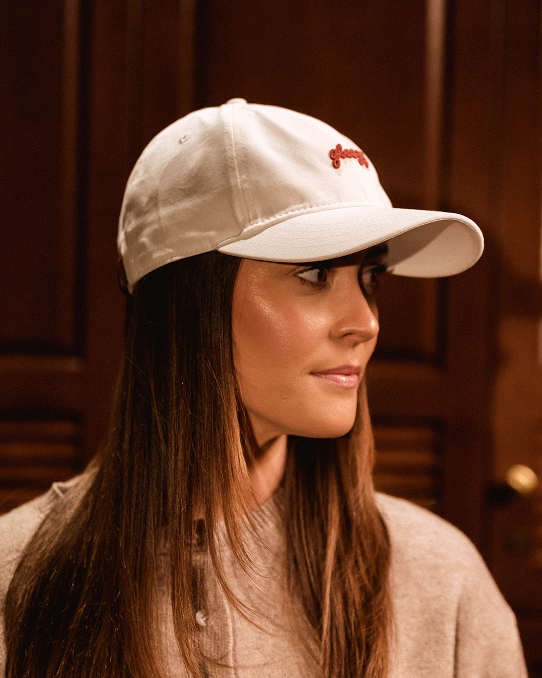 Woman wearing the white Gleezy script dad hat, side profile view