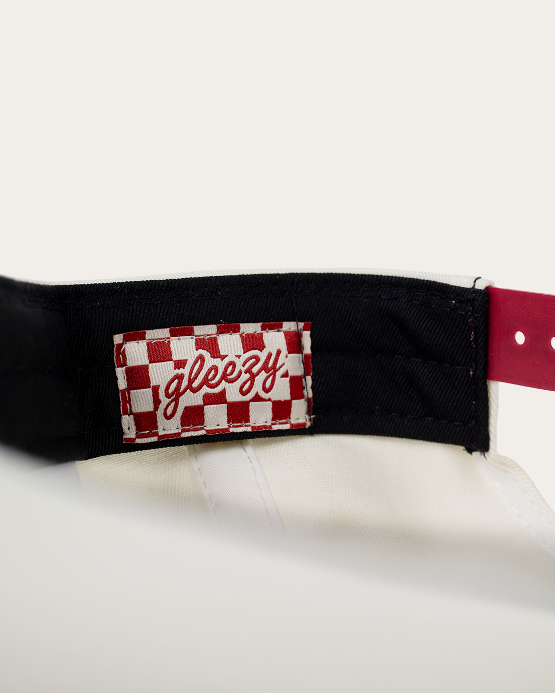 Close-up of the cream hat's inner brim showing a woven red-and-cream checkered Gleezy label