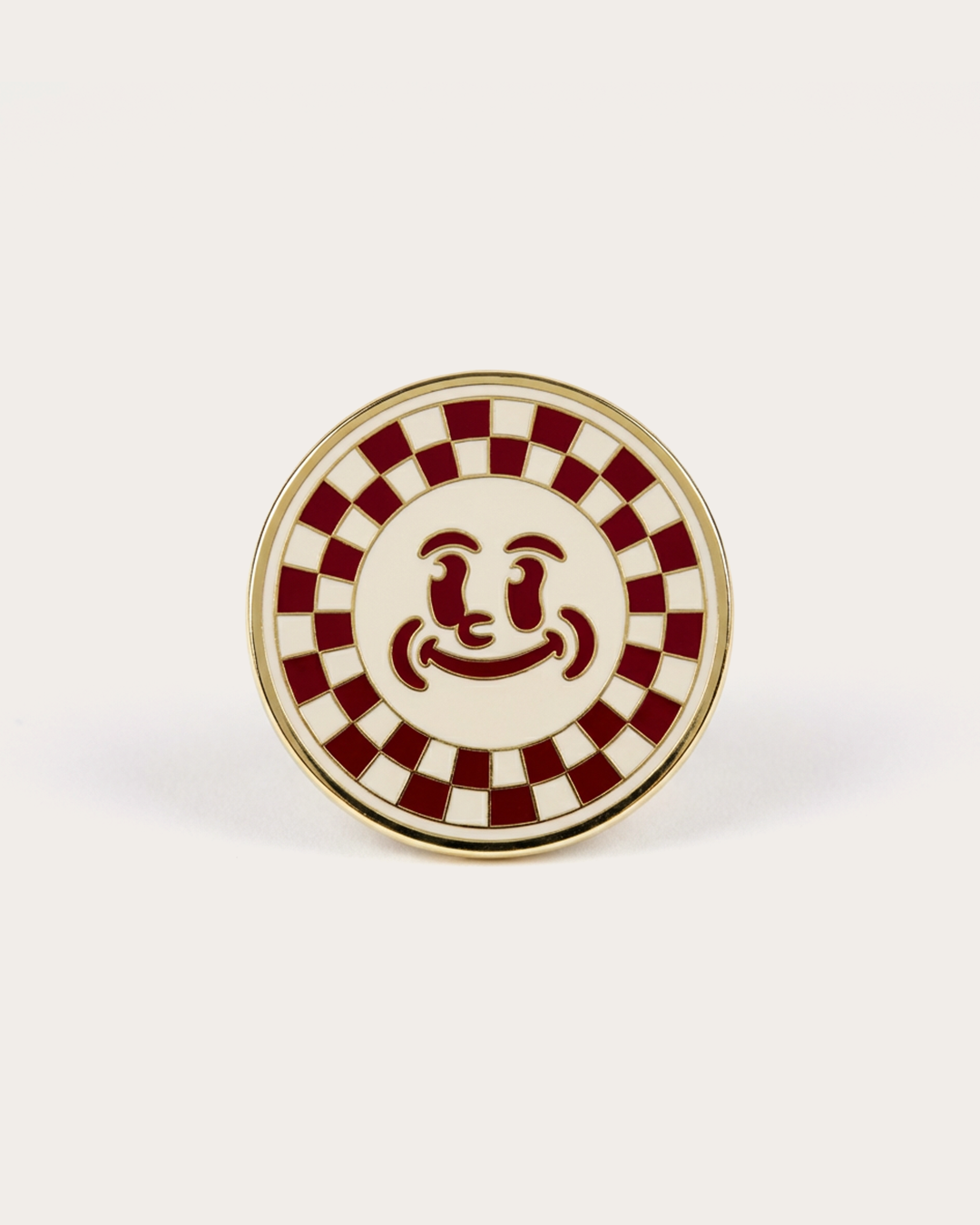 Round decorative pin with a checkered pattern and central design on a white background