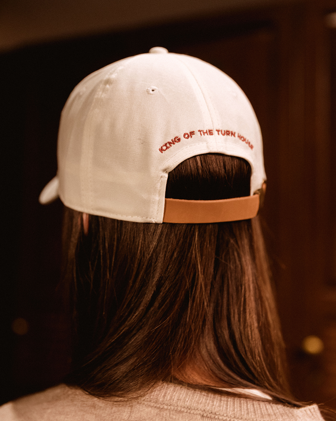 Back view of a woman wearing the white dad hat embroidered with 'King of the Turn House'