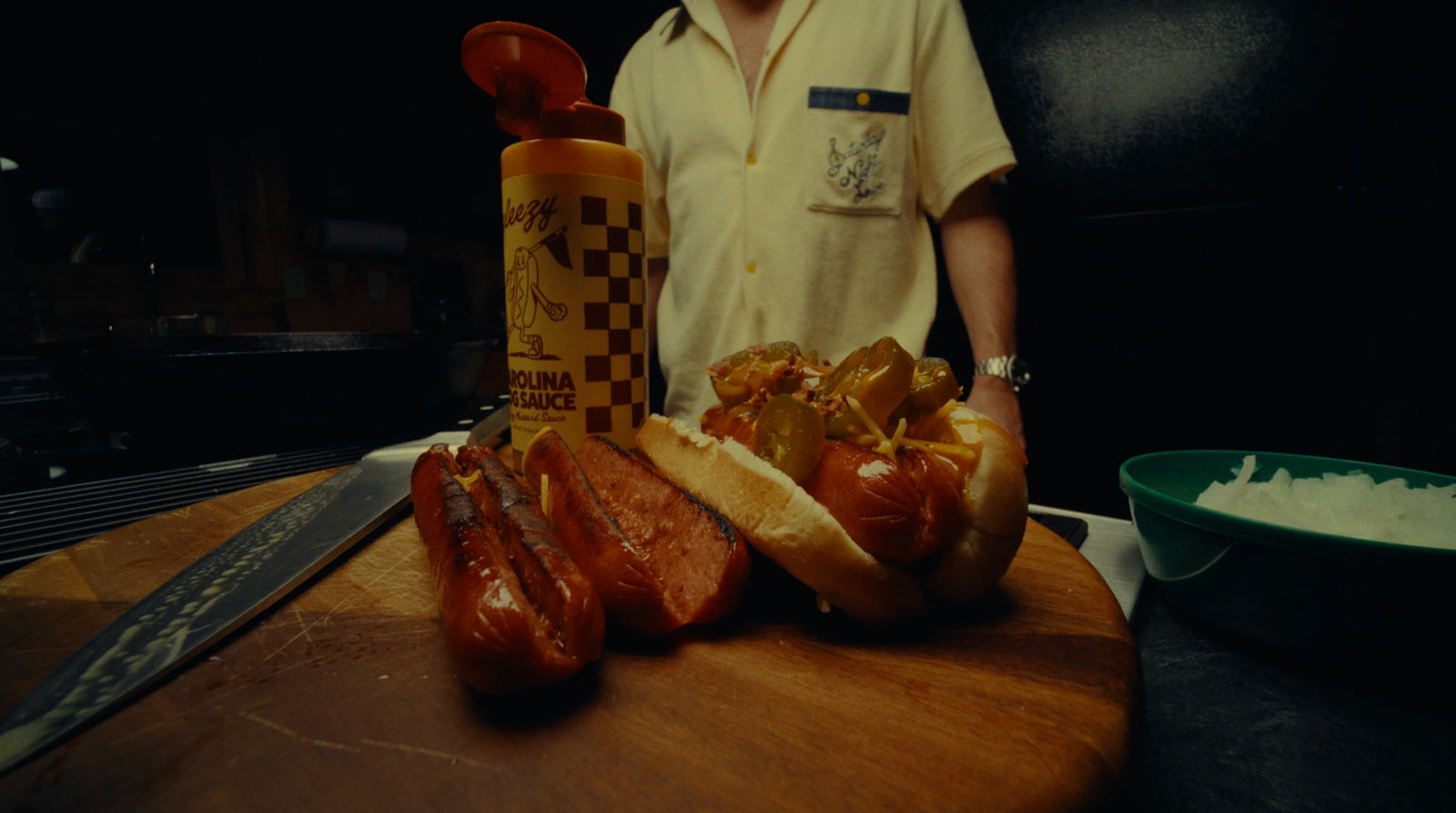 Hot dogs on a wooden board with a person in the background
